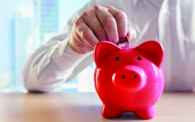 Ein Herr steckt Geld in ein Sparschwein Ein Herr steckt Geld in ein Sparschwein