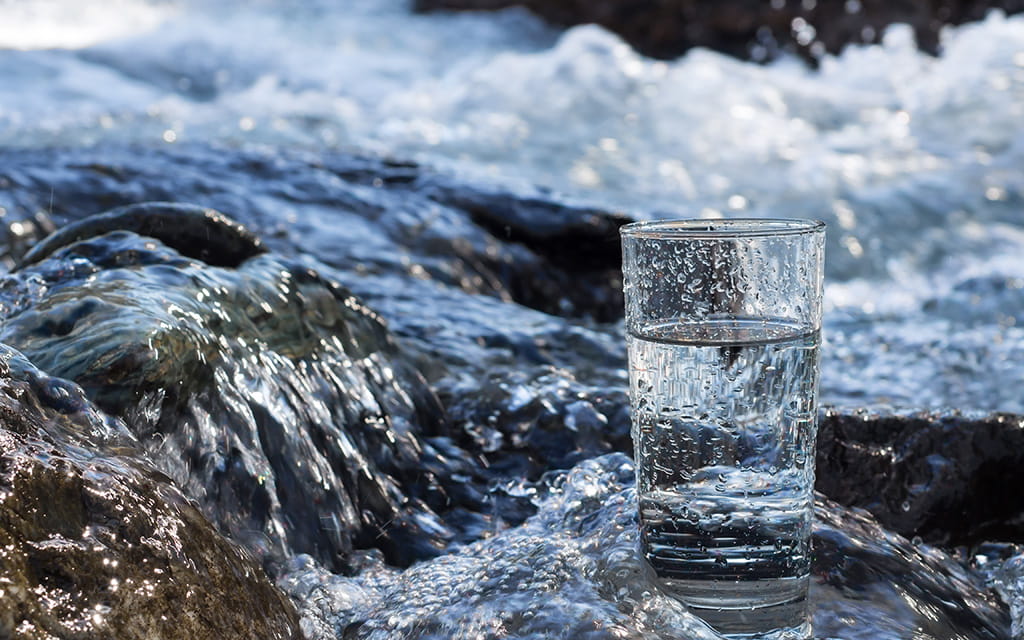 Wasserglas steht an einem Bach