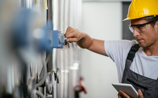 Junger Mann mit Tablet überprft eine Erdgasanlage
