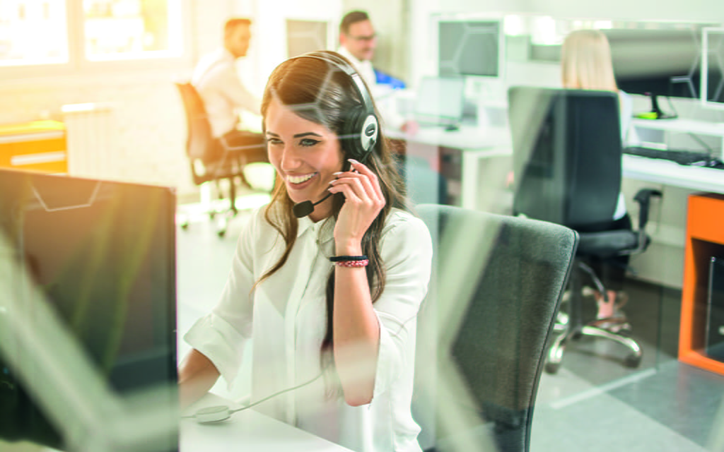 Junge Dame telefoniert am Arbeitsplatz über ein Headset