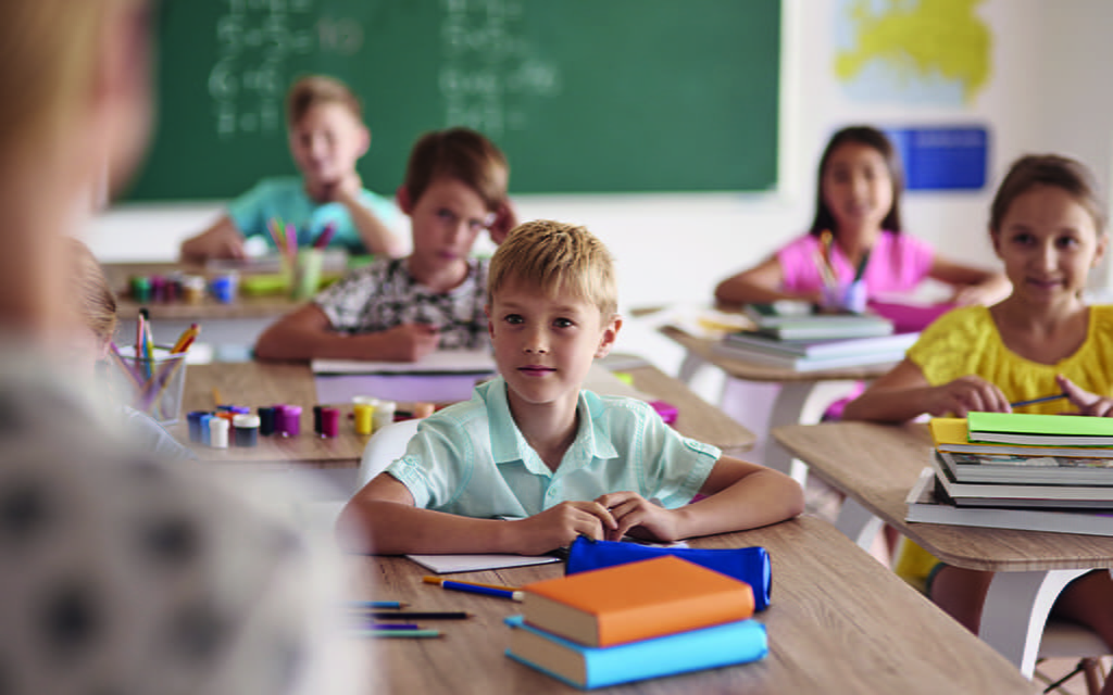 Schüler sitzen im Klassenraum und hören der Lehrerin zu